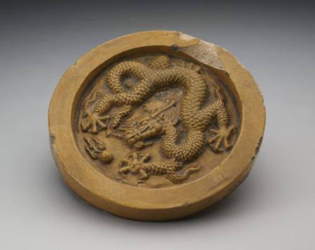 One of a pair of circular roof tiles with dragon design in high relief on circumferential wall.