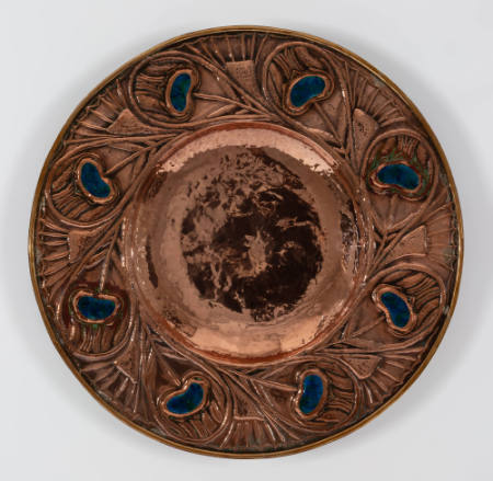 Plaque with peacock feather pattern including blue colored, kidney-shaped inlay