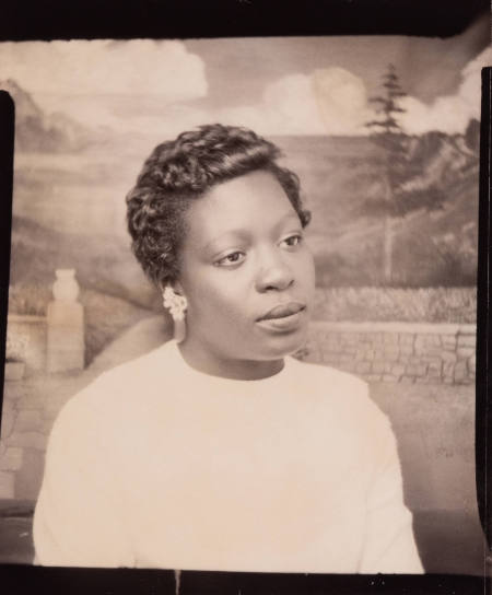 Photo booth portrait of a woman with styled hair and wearing earrings