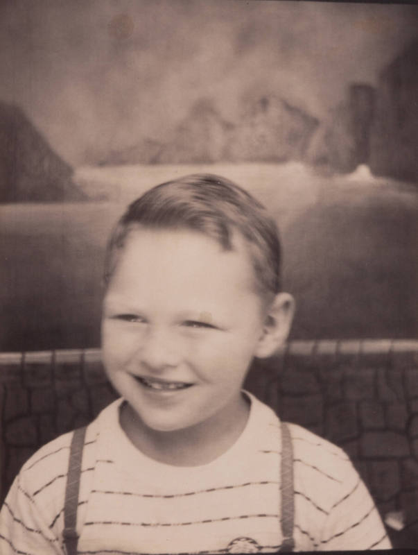 Photo booth portrait of a laughing little boy wearing narrow suspenders