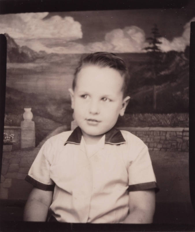 Photo booth portrait of a little boy wearing a short sleeved shirt with a dark collar and dark cuffs