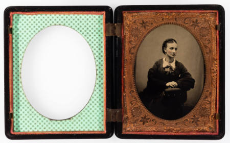 Untitled [Young woman leaning against arm of chair she's sitting in, cheeks enhanced in red]