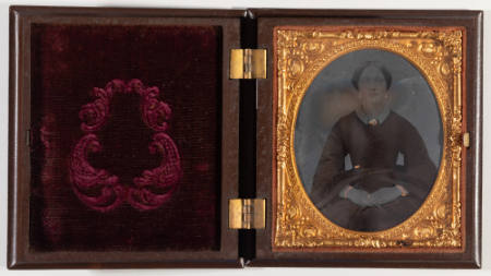 Untitled [Young seated woman, hands clasped, cheeks enhanced in red, jewelry painted gold]