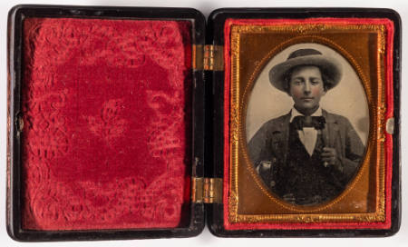 Untitled [Young man in hat, holding his left lapel in his left hand, cheeks enhanced in red]