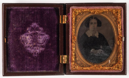 Untitled [Seated woman, hands clasped in lap, cheeks enhanced in red]