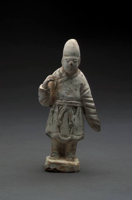 Figurine of an attendant dressed in a robe tied at the waist, wearing an oval cap, his right arm raised