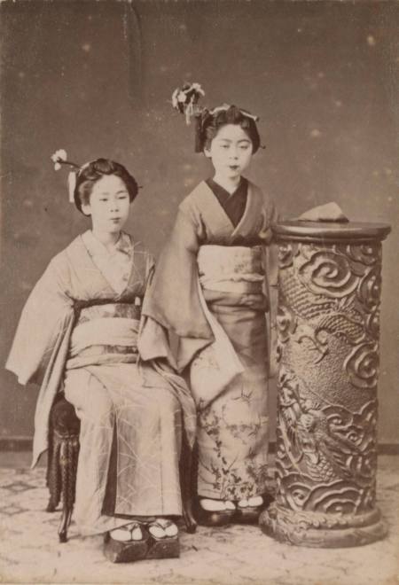 [Two woman next to a column]