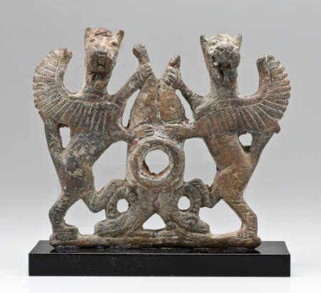 Cheekpiece from a horse bit with design of a pair of griffins in combat with an ibex