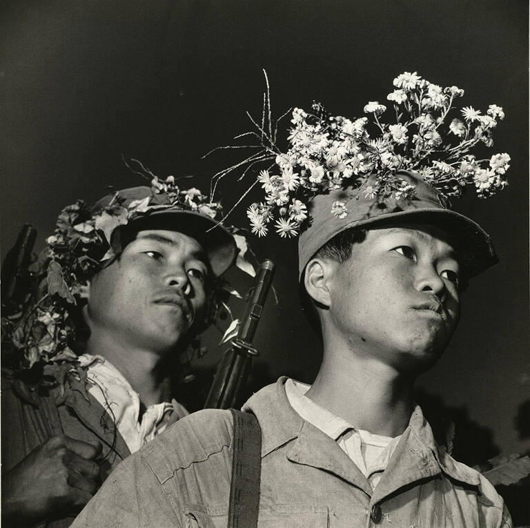 [Two youthful Volunteer Police wearing hats for camouflage in the deadly game of guerilla warfare]