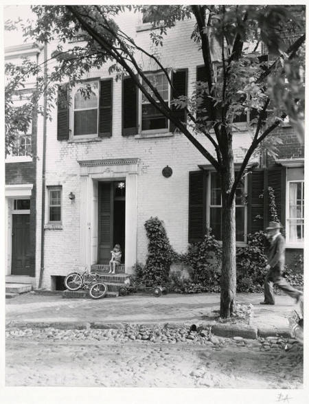 [Girl on rowhouse steps with bike]