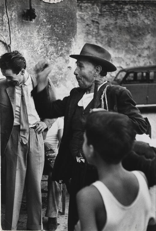 Luigi, a local tramp, stops regularly in the piazza for wine and to entertain the crowds with his stories, Italy