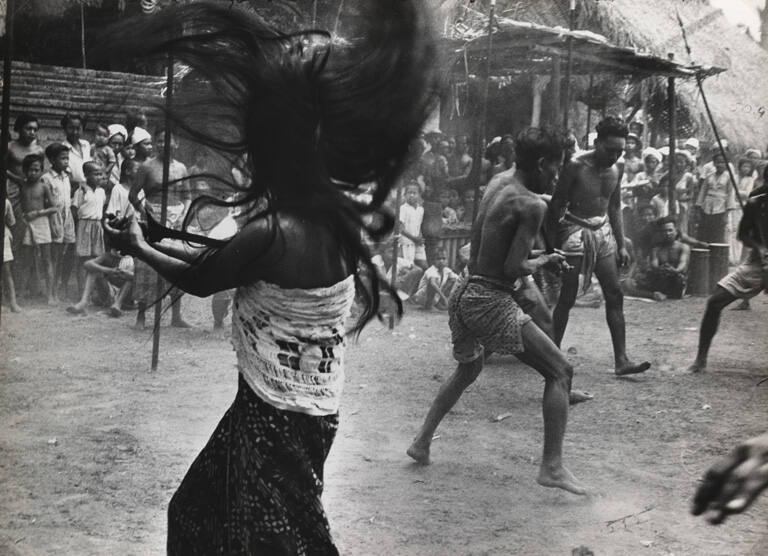 Trance dancers depict a struggle against a witch's blade while bystanders are whipped to a frenzy, Indonesia