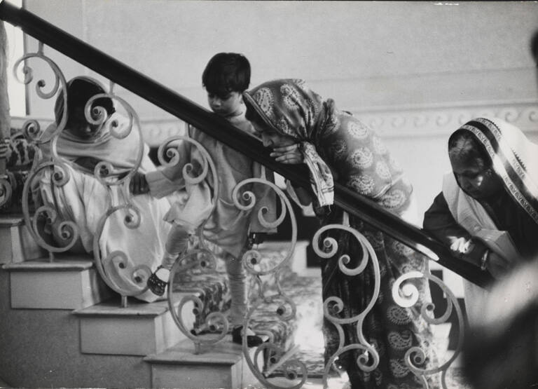 Women and children looking down from a staircase as Gandhi's body is removed for his funeral, New Delhi, India