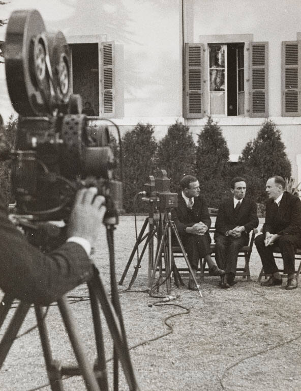 Dr. Goebbels (center) just before broadcasting at the Geneva Conference talking with two collaborators