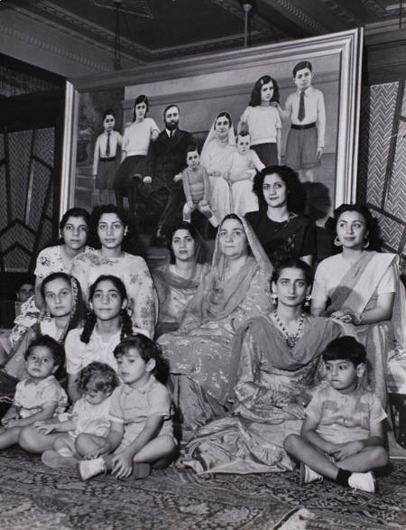 [Lady Nursrat Haroon, Muslim League activist and heiress to a sugar fortune, with the female members of her family in front of a family portrait, Karachi, Pakistan]