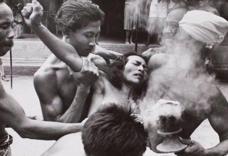 Kris trance dancer being revived by temple attendants, Batubulan, Bali