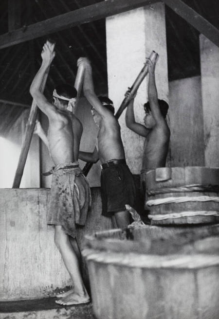 Three men stirring batiks in giant vats in order to wash out wax, Indonesia