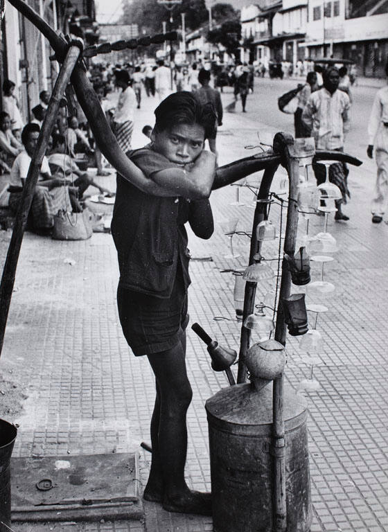 Street vendor leaning on his carrier stand of wine glasses, Indonesia