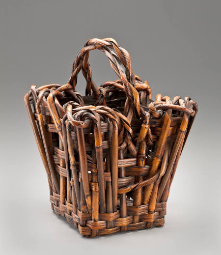 Squat basket having a slightly "splayed" form, and composed of hearty, boldly woven materials