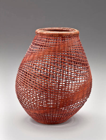 Honey colored, delicate basket with slightly "open" weave, and mouth formed by a round ring