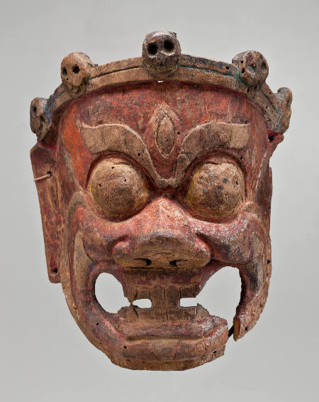 Mask with bared teeth, bulging eyes, and five skull-like faces decorating a crown on top